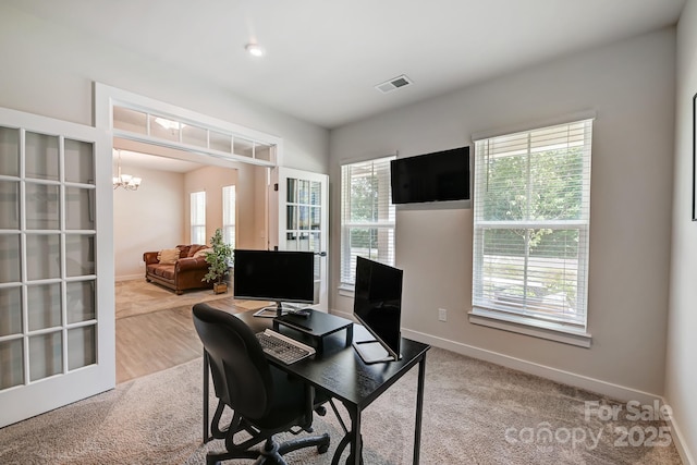 office with carpet and a notable chandelier