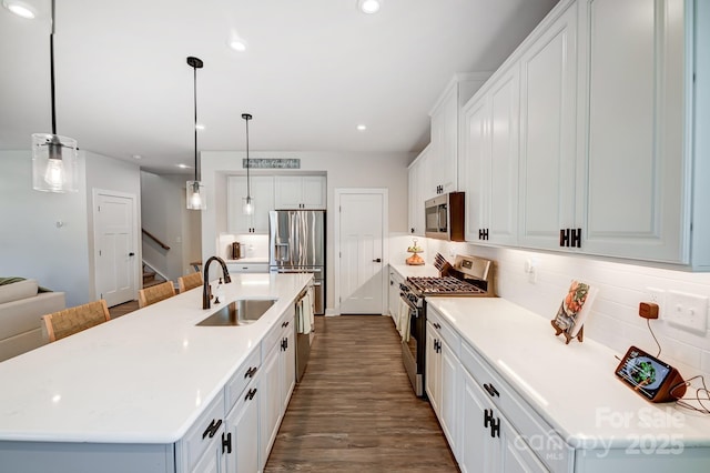 kitchen with sink, white cabinets, stainless steel appliances, and a center island with sink