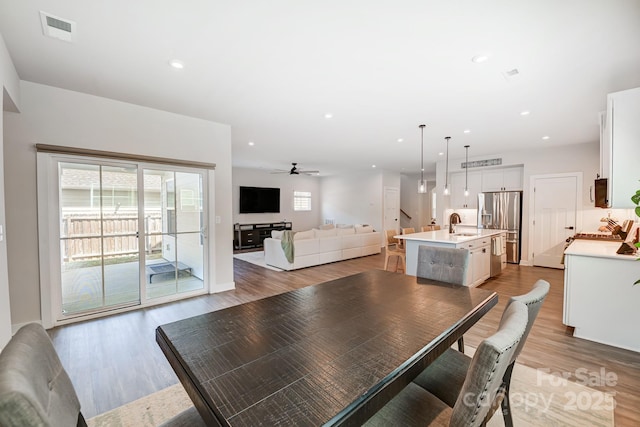 dining room featuring ceiling fan, sink, and light hardwood / wood-style flooring