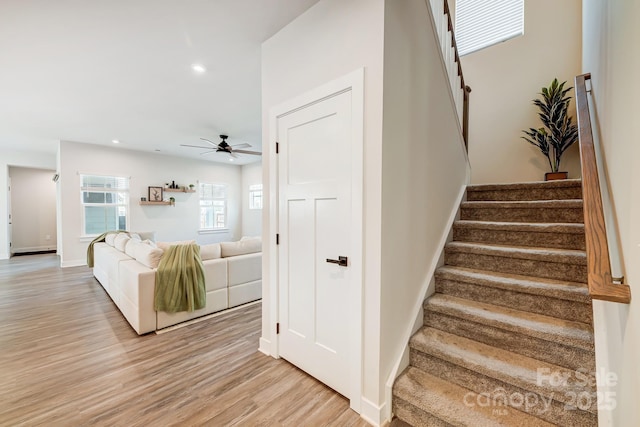 stairs featuring hardwood / wood-style flooring and ceiling fan