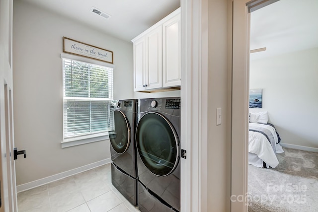 washroom featuring washing machine and clothes dryer, light tile patterned flooring, and cabinets