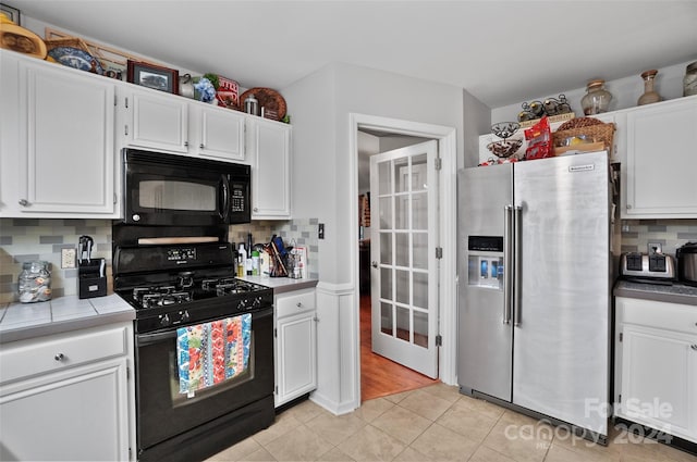 kitchen featuring backsplash, light hardwood / wood-style floors, white cabinets, and black appliances