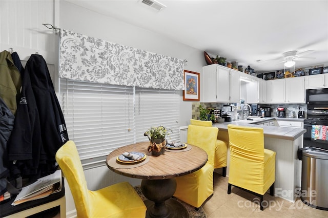 kitchen with backsplash, light tile patterned floors, tile counters, white cabinetry, and stove