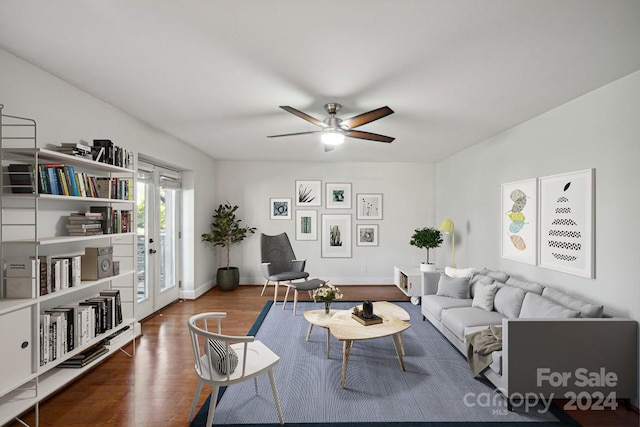 living room featuring a ceiling fan, baseboards, and wood finished floors