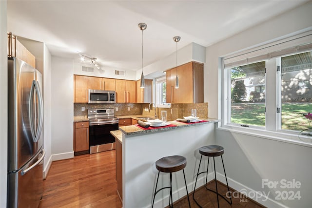 kitchen with a peninsula, visible vents, stainless steel appliances, and backsplash