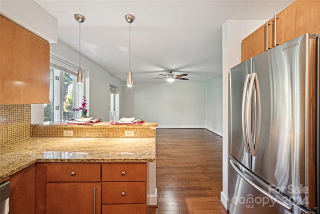 kitchen featuring a peninsula, appliances with stainless steel finishes, brown cabinets, and dark wood-style flooring