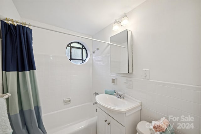 full bath featuring toilet, shower / tub combo, vanity, and tile walls