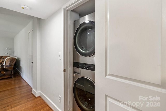 laundry room with laundry area, baseboards, wood finished floors, and stacked washer and clothes dryer