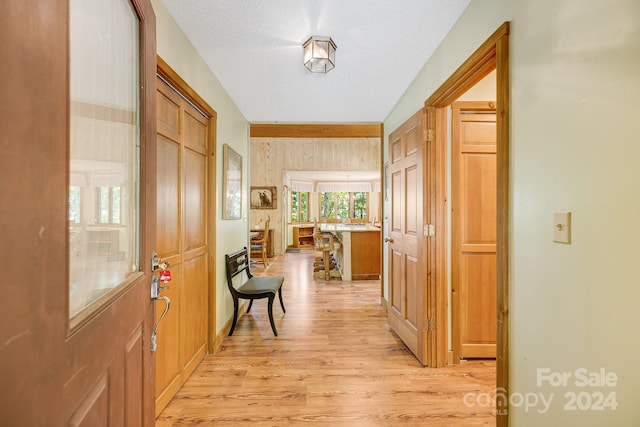 corridor with light wood-type flooring and a textured ceiling