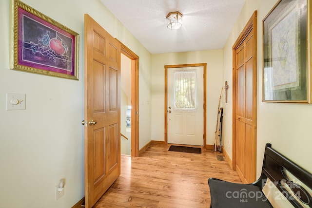 doorway to outside featuring a textured ceiling and light hardwood / wood-style flooring