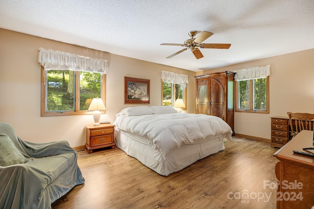 bedroom with ceiling fan, a textured ceiling, and light hardwood / wood-style flooring