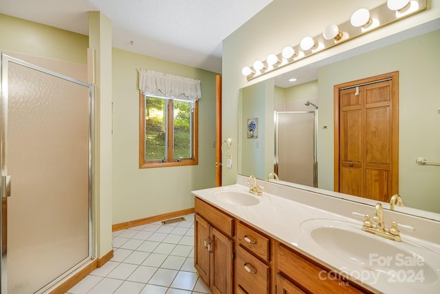 bathroom with a textured ceiling, dual vanity, walk in shower, and tile patterned floors