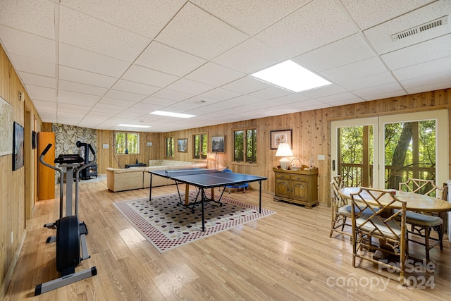 recreation room with light wood-type flooring, wood walls, and a paneled ceiling