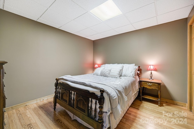 bedroom with a paneled ceiling and light hardwood / wood-style floors