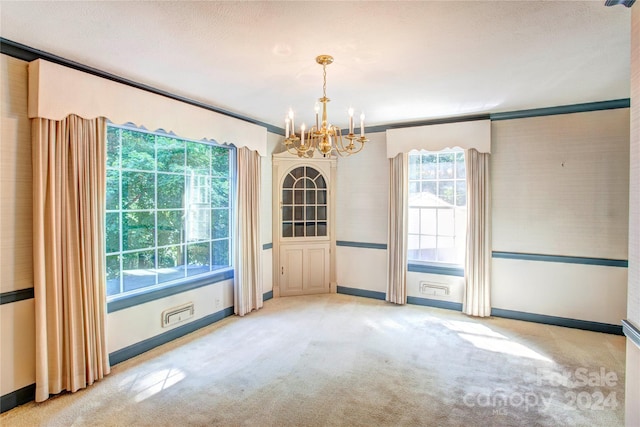 carpeted spare room with ornamental molding and a chandelier