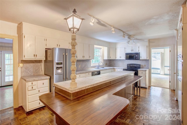 kitchen featuring parquet floors, sink, ceiling fan, white cabinetry, and black appliances