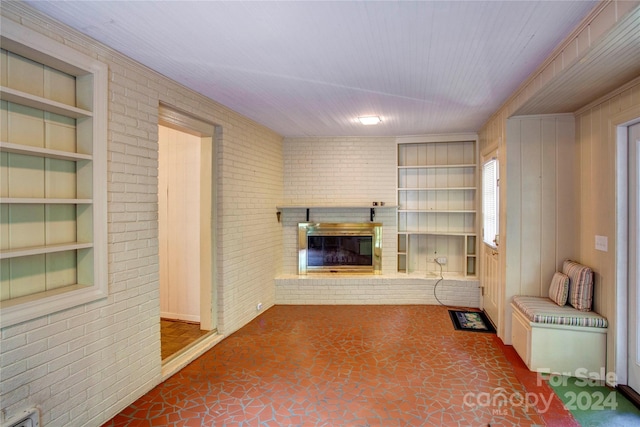 interior space featuring built in shelves, brick wall, tile patterned floors, and a fireplace