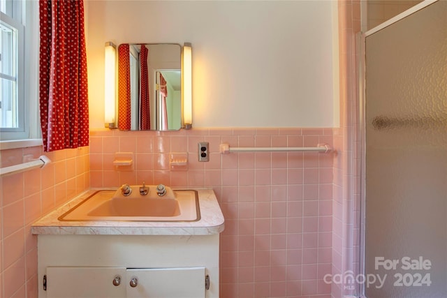 bathroom featuring a shower with door, decorative backsplash, vanity, and tile walls