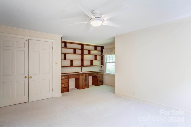 unfurnished bedroom with ceiling fan, light carpet, a closet, and built in desk