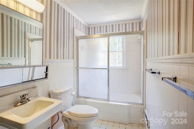 full bathroom with bath / shower combo with glass door, tile patterned floors, a textured ceiling, tile walls, and toilet