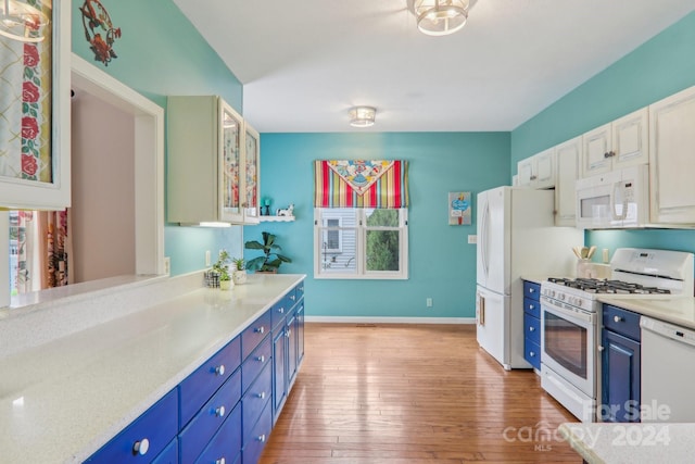 kitchen with white appliances, blue cabinetry, white cabinetry, and light wood-type flooring