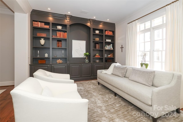 living room featuring built in features, crown molding, and light wood-type flooring