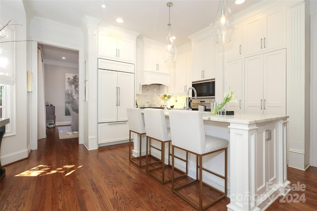 kitchen featuring dark wood-type flooring, decorative backsplash, an island with sink, white cabinetry, and built in appliances