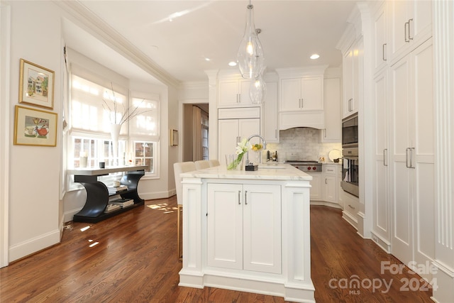 kitchen featuring dark hardwood / wood-style flooring, decorative backsplash, an island with sink, white cabinetry, and pendant lighting