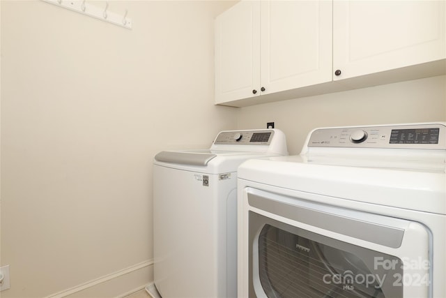 washroom with washing machine and dryer and cabinets