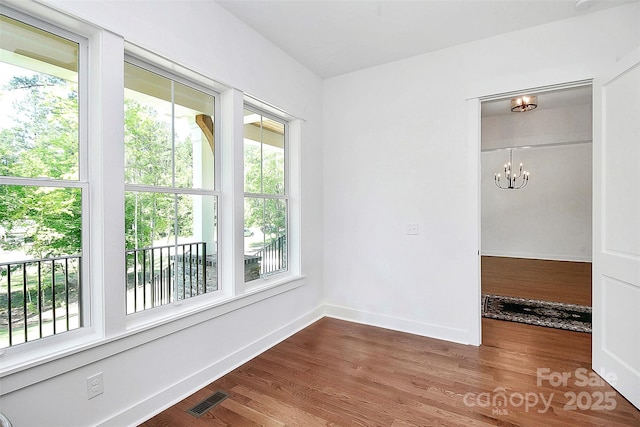 empty room with a notable chandelier and wood-type flooring