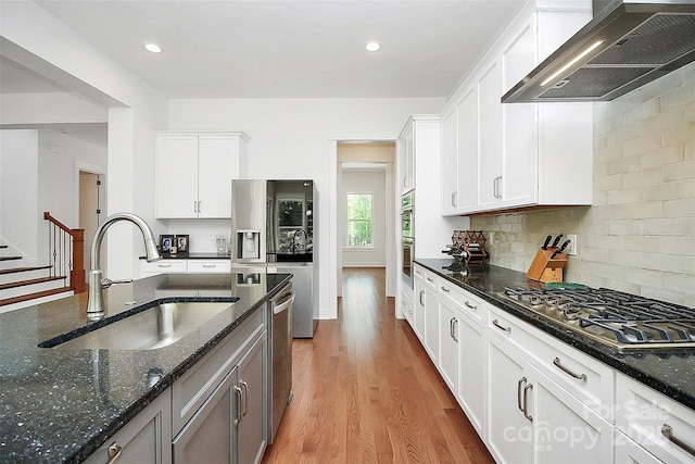 kitchen featuring appliances with stainless steel finishes, extractor fan, dark stone counters, and white cabinets