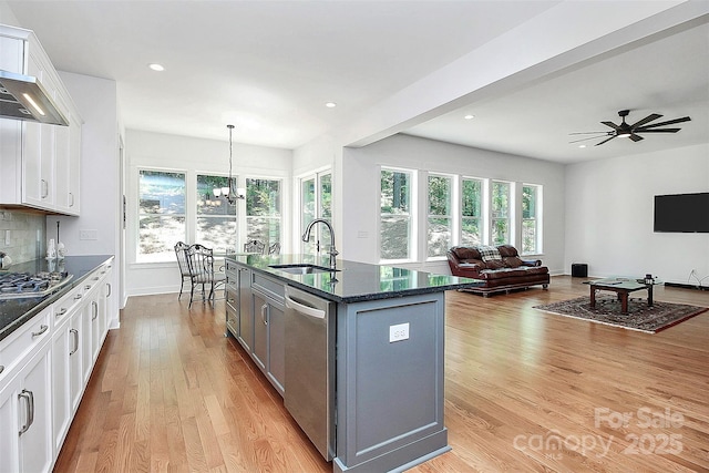 kitchen featuring appliances with stainless steel finishes, pendant lighting, sink, white cabinets, and a center island with sink