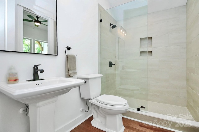 bathroom featuring hardwood / wood-style flooring, toilet, and a tile shower