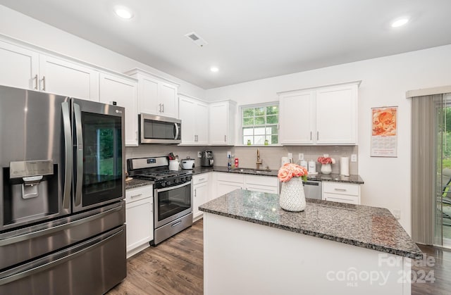 kitchen featuring dark stone countertops, stainless steel appliances, a center island, and white cabinets