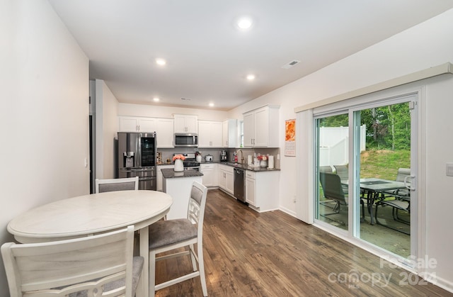 kitchen with backsplash, dark hardwood / wood-style floors, white cabinets, appliances with stainless steel finishes, and a center island