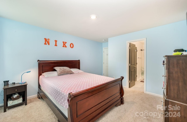 bedroom featuring light colored carpet and ensuite bath