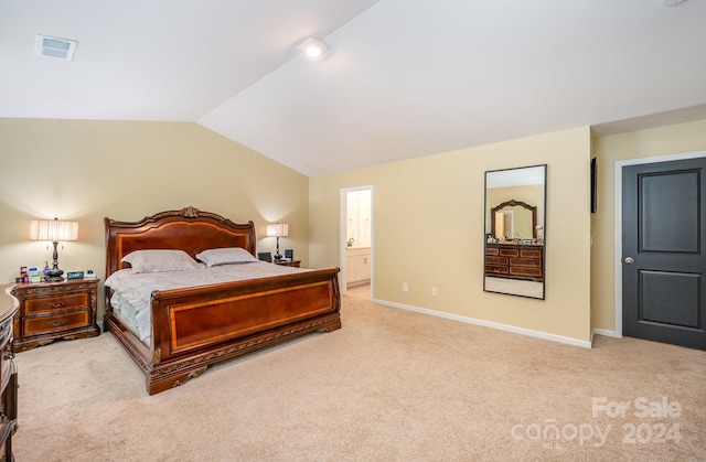 bedroom featuring light colored carpet, ensuite bathroom, and lofted ceiling