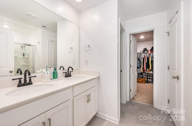 bathroom featuring tile patterned flooring, dual vanity, and a shower with shower door