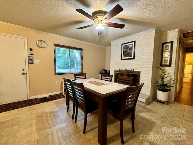 tiled dining space featuring ceiling fan, a fireplace, crown molding, and a textured ceiling