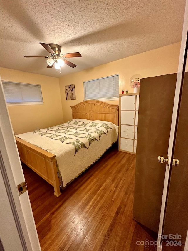 unfurnished bedroom featuring dark wood-type flooring, a textured ceiling, and ceiling fan