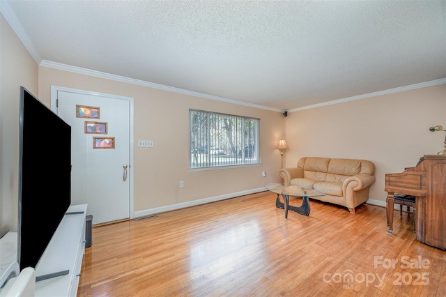 living room with visible vents, light wood-style flooring, a textured ceiling, crown molding, and baseboards