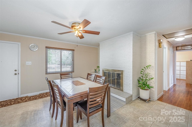 dining area featuring baseboards, a ceiling fan, ornamental molding, and a fireplace