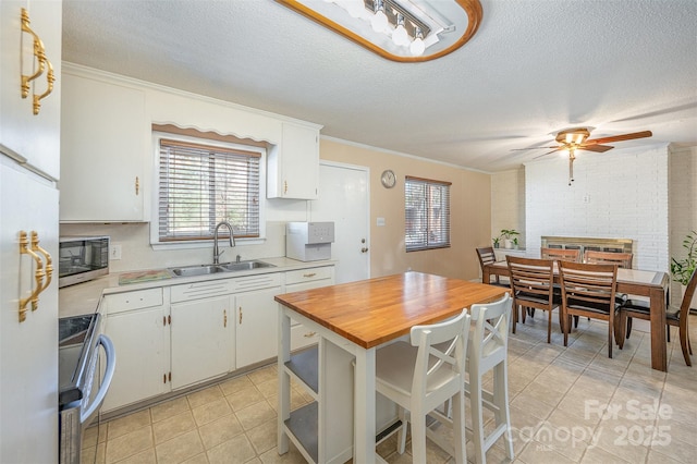 kitchen with stainless steel microwave, white cabinetry, electric range oven, and a sink