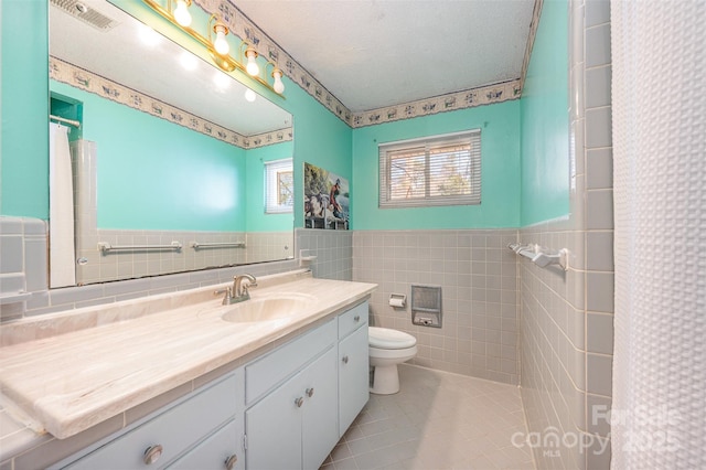 full bath with tile walls, a wainscoted wall, toilet, tile patterned floors, and vanity