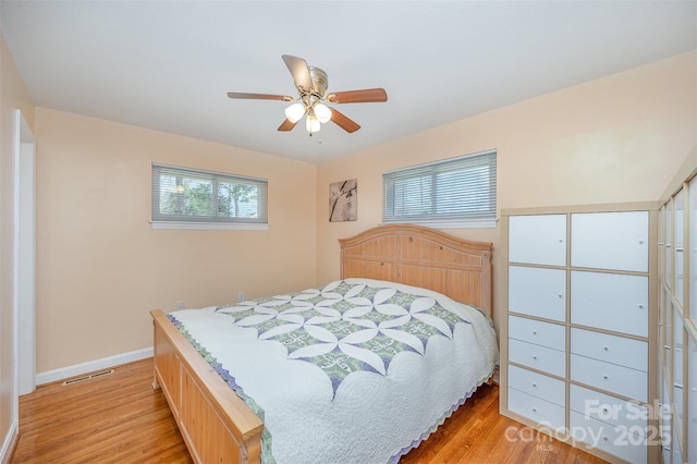 bedroom featuring light wood-style flooring, baseboards, visible vents, and ceiling fan