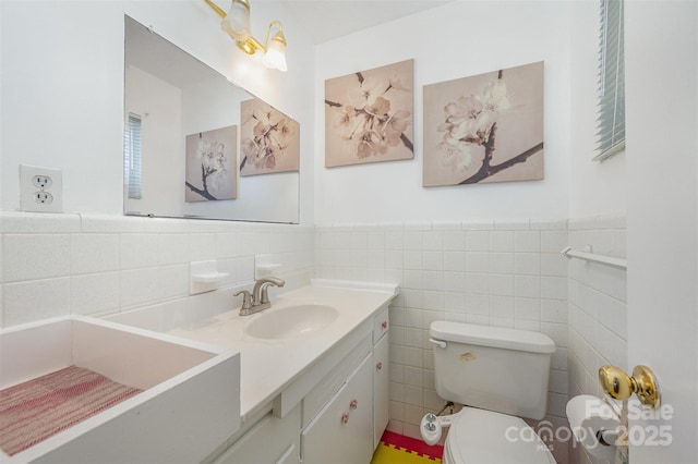 bathroom featuring tile walls, wainscoting, toilet, and vanity