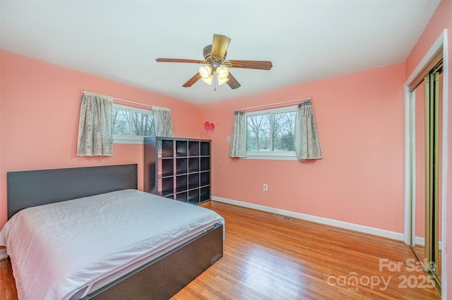 bedroom with visible vents, multiple windows, baseboards, and wood finished floors