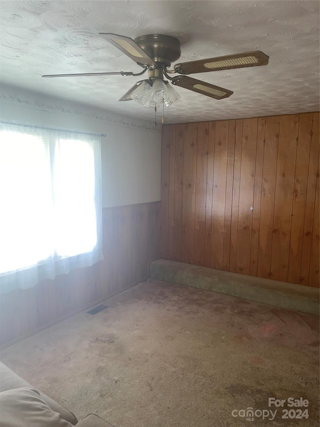 carpeted empty room with visible vents and wood walls