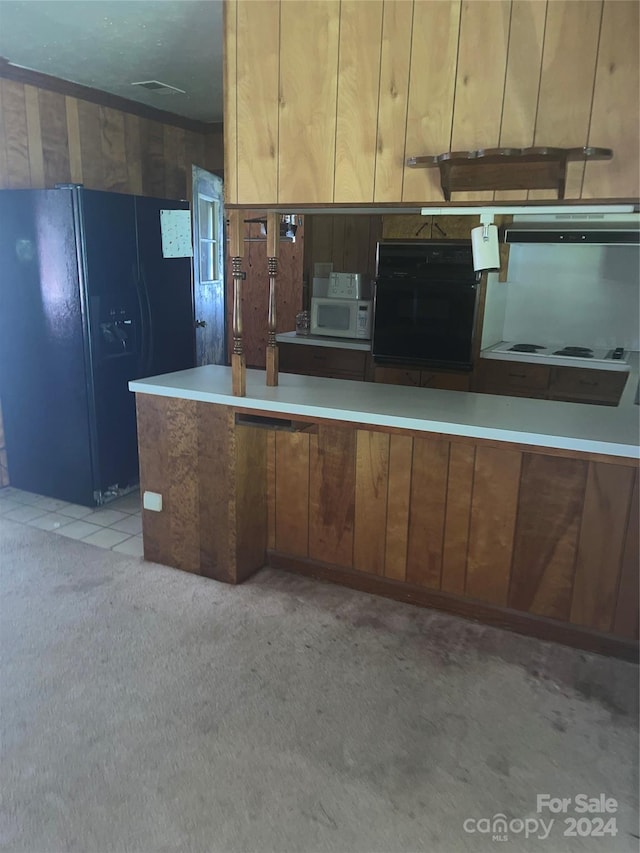 kitchen featuring black appliances, brown cabinets, and light colored carpet