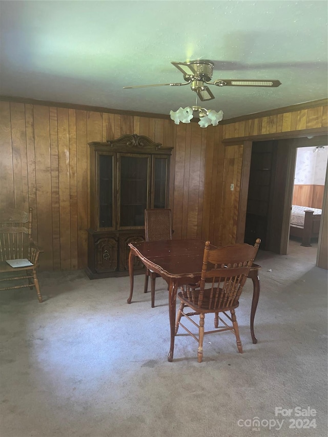 dining room with ceiling fan, ornamental molding, and wooden walls